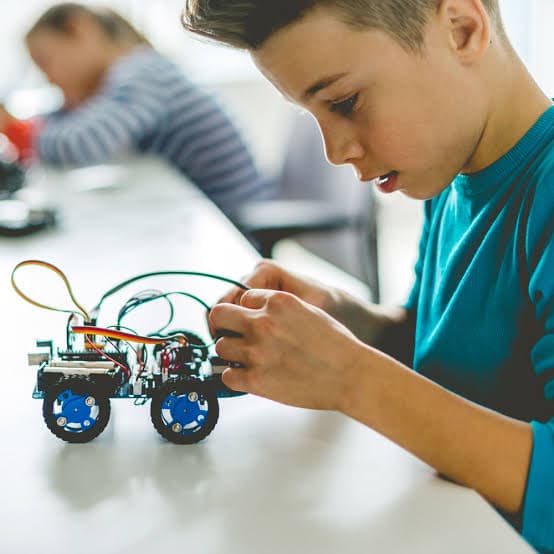 Estudiante armando un robot con ruedas